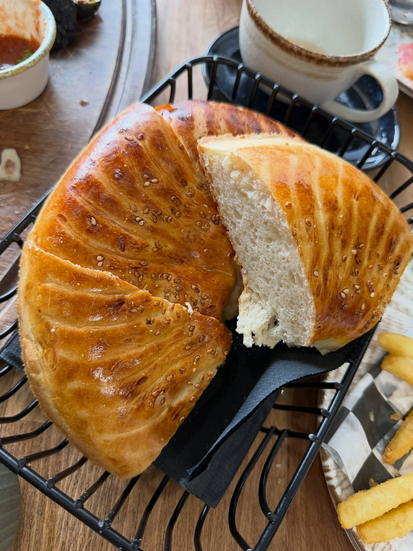 Round Uzbek bread torn open beside a pot of tea